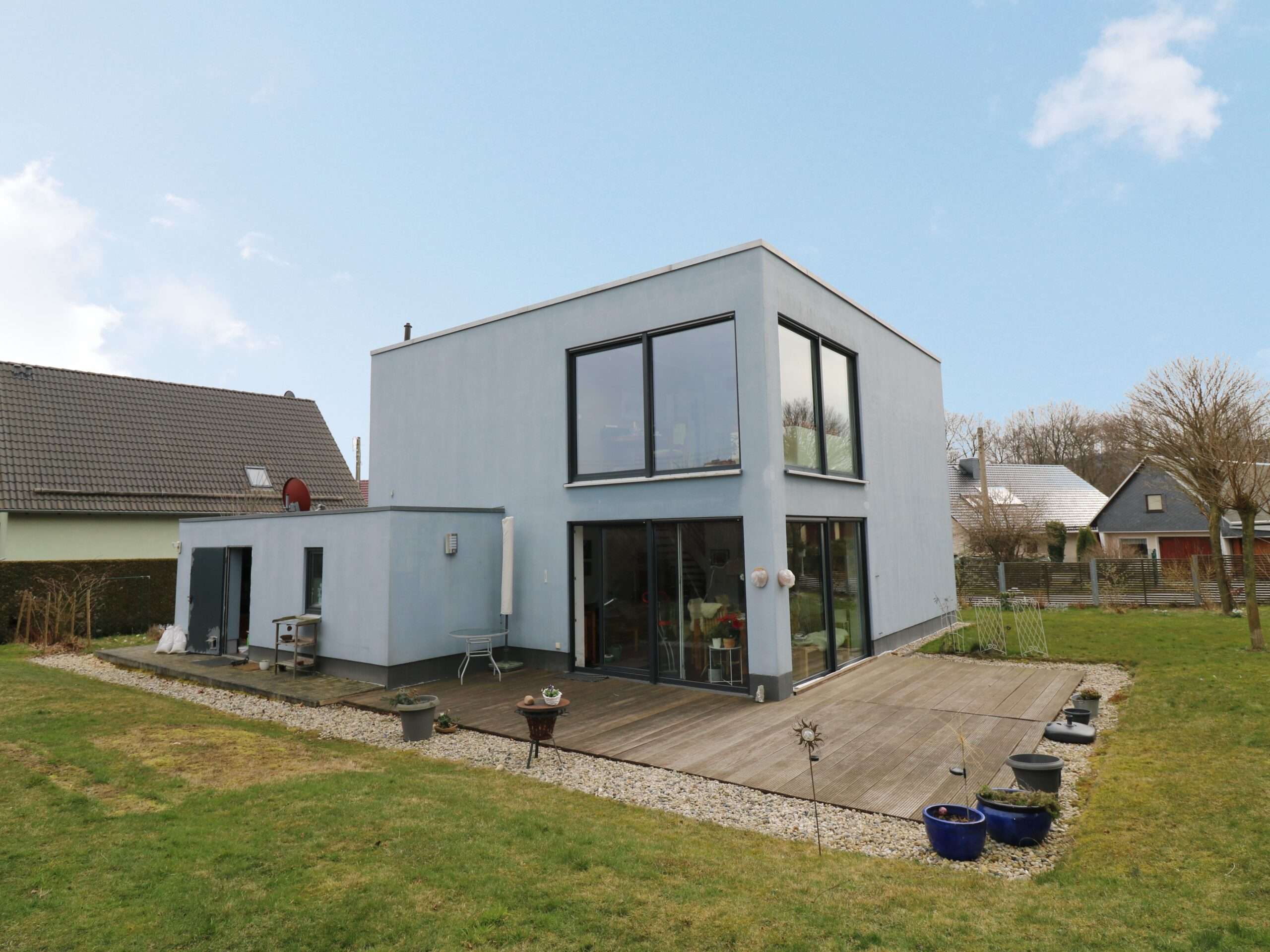 Haus im Bauhausstil mit Holzterasse im Grünen